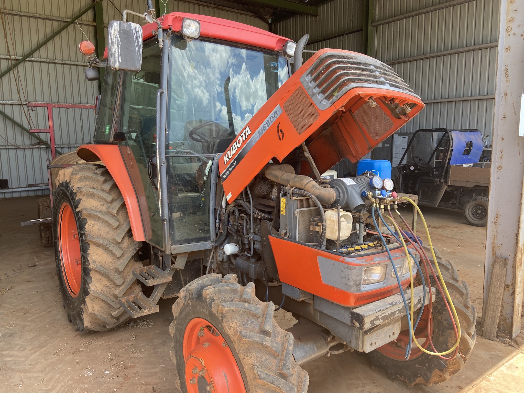 Kubota M6800 tractor in a shed with the bonnet up and air-conditioning gauges connected