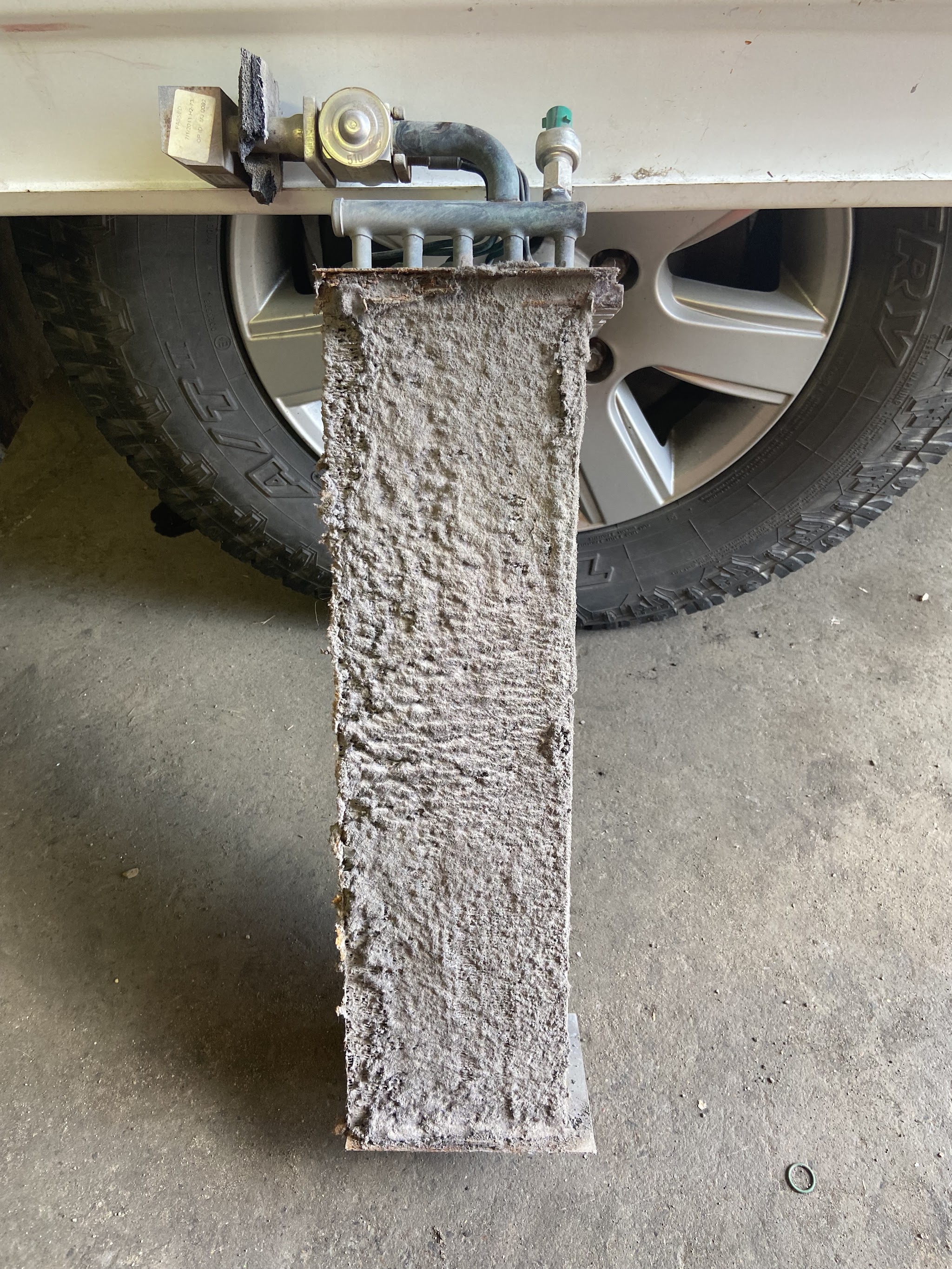 A condenser removed from under a vehicle, completely matted with grey dust and lint