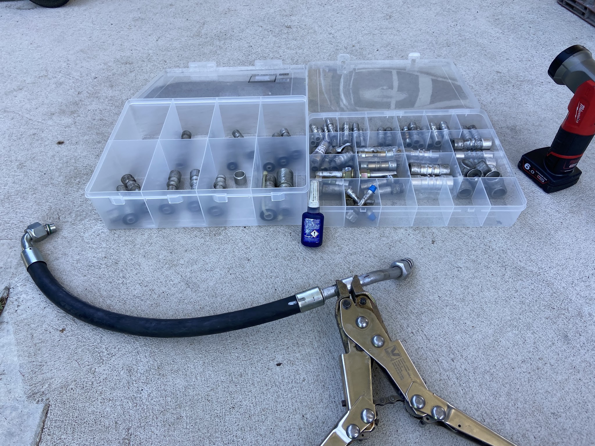 Organiser trays of air-conditioning hose fittings and ferrules with a made up hose and crimping pliers